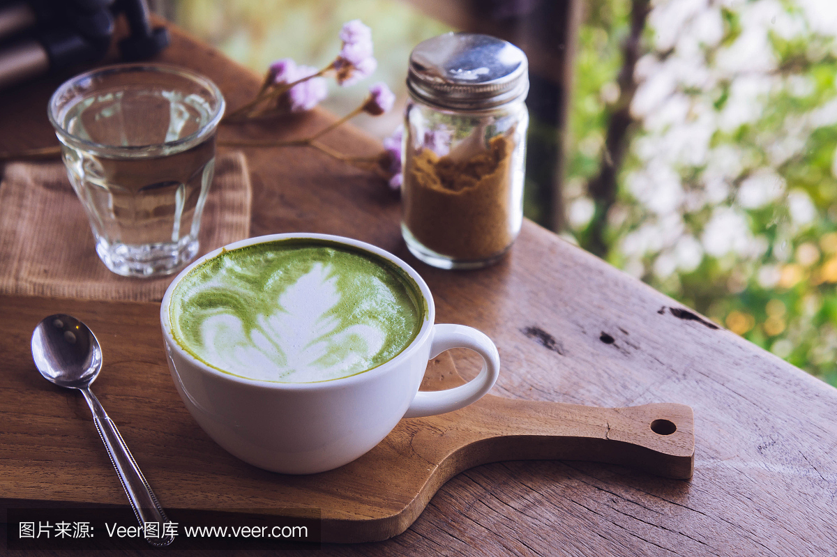 木桌上的绿茶热饮拿铁白杯,香气袭人,咖啡厅休闲时光